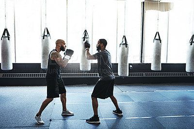 Buy stock photo Shot of a male boxer practising his moves with his coach