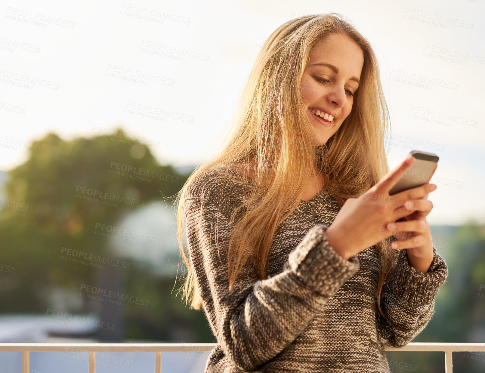Buy stock photo Cropped shot of an attractive young woman texting on her cellphone outside