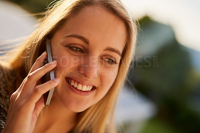 Buy stock photo Cropped shot of an attractive young woman talking on a cellphone outside