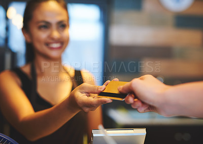 Buy stock photo Shot of a young barista accepting payment from a customer in a coffee shop