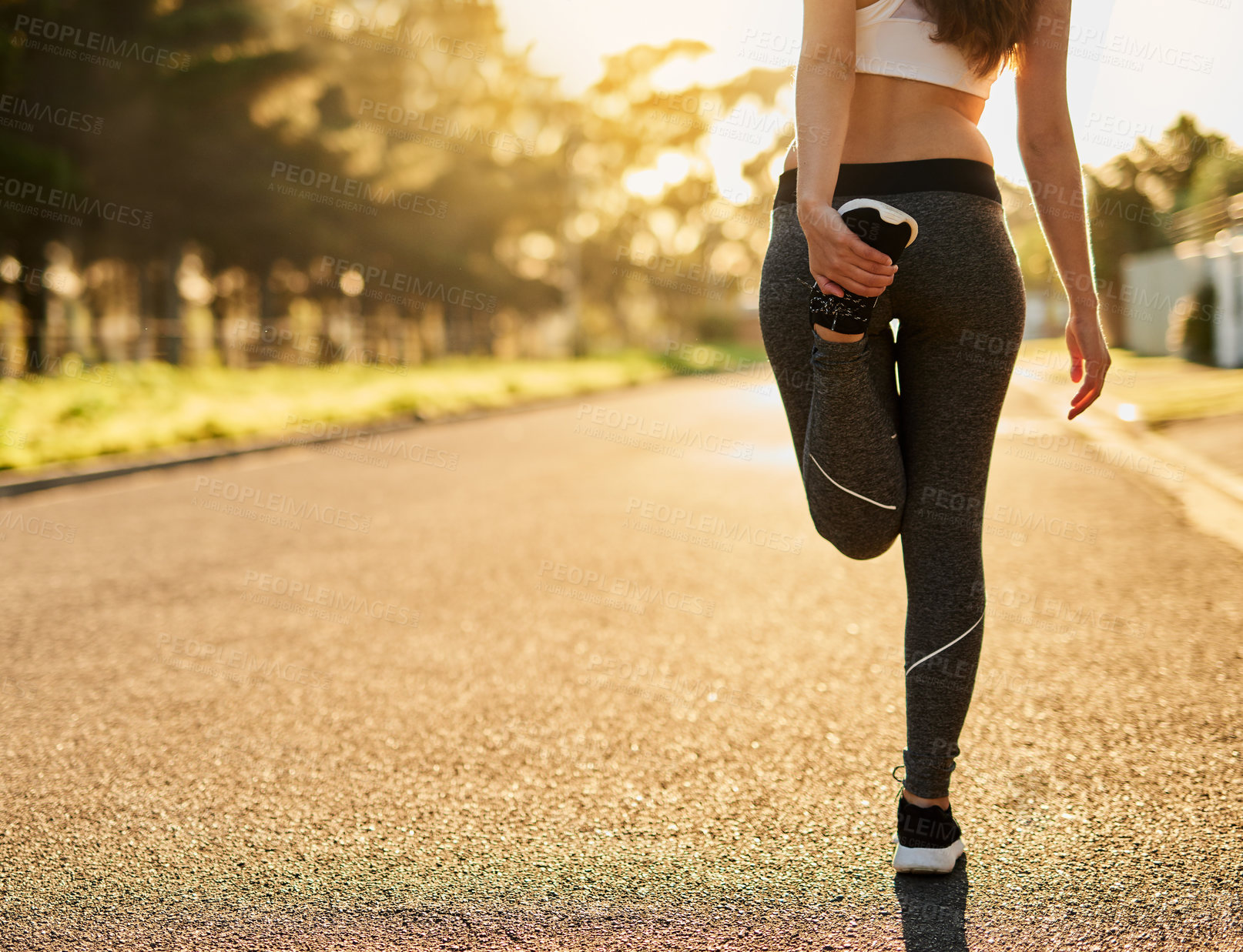 Buy stock photo Rearview shot of an unidentifiable young woman stretching before a run