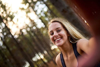 Buy stock photo Portrait of a happy young woman taking a selfie while exploring a forest on her own
