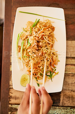Buy stock photo Shot of a person eating a bowl of pad thai in a restaurant in Thailand