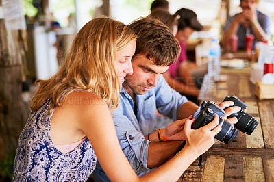 Buy stock photo Shot of a young couple looking at pictures on their camera while on holiday in Thailand
