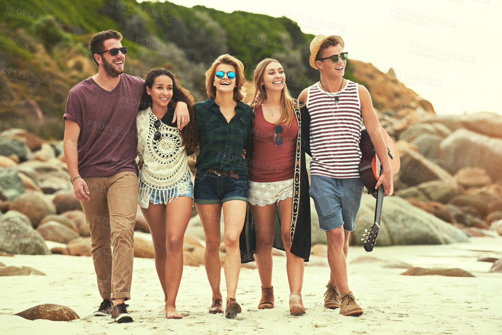 Buy stock photo Full length shot of a group of friends walking on the beach on a summer's day