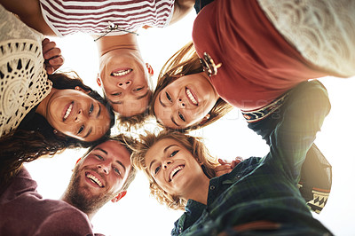 Buy stock photo Low angle portrait of a group of friends standing in a huddle on the beach