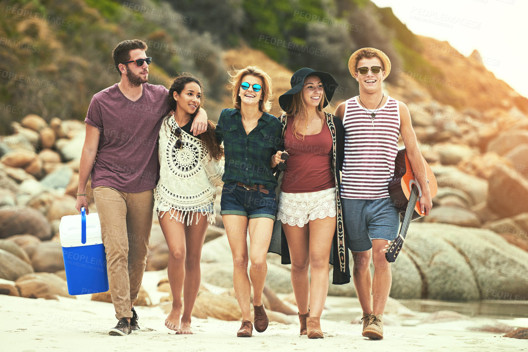 Buy stock photo Full length shot of a group of friends walking on the beach on a summer's day