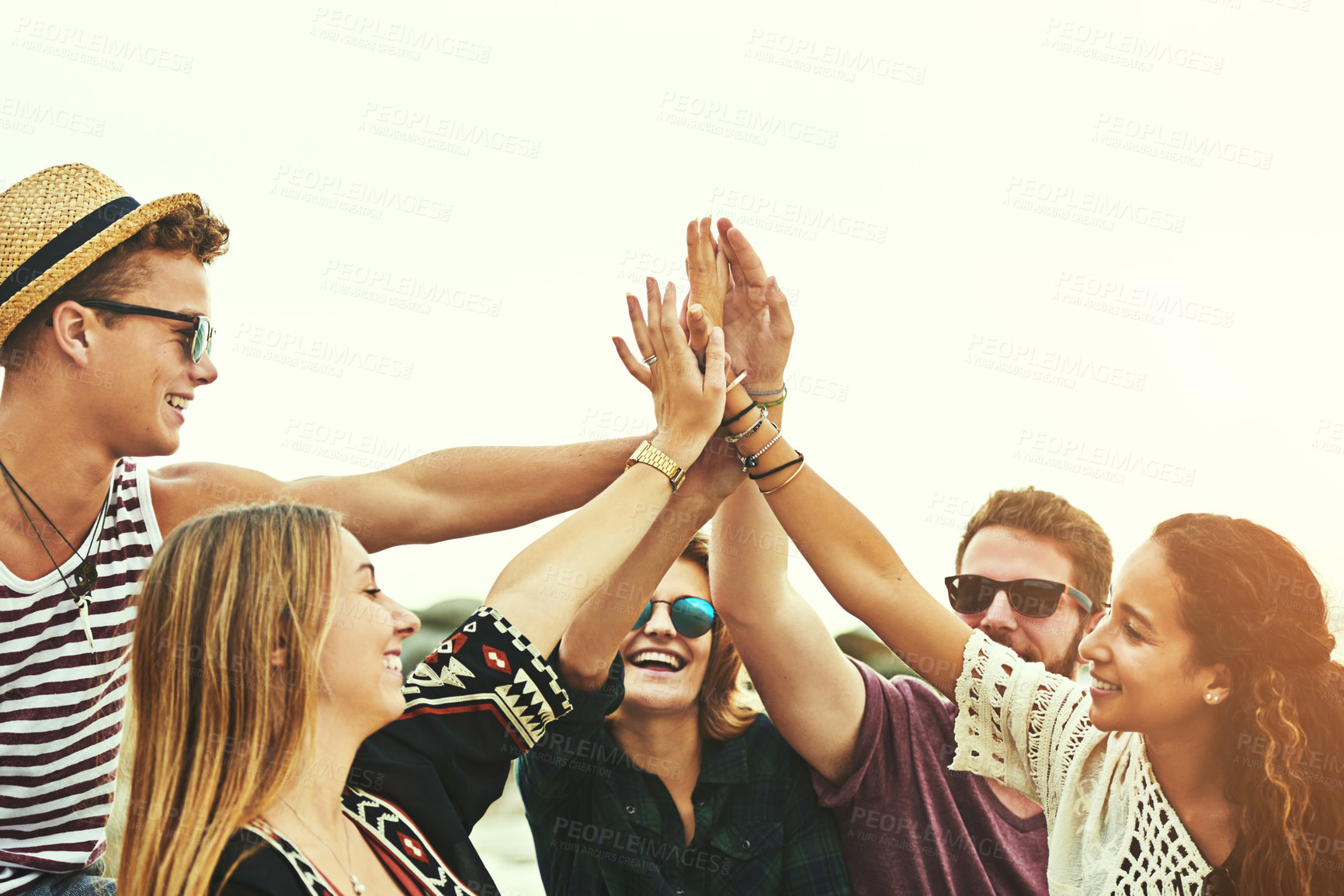 Buy stock photo Cropped shot of a happy group of friends high fiving on the beach