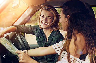 Buy stock photo Cropped shot of two young friends reading a map while on a roadtrip together