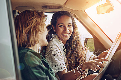 Buy stock photo Cropped shot of two young friends reading a map while on a roadtrip together