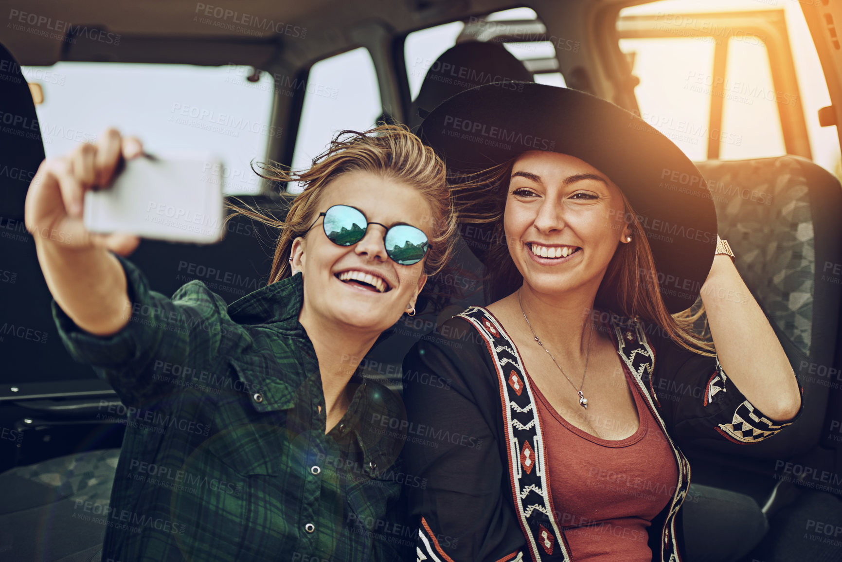 Buy stock photo Cropped shot of two young friends taking a selfie while on a roadtrip together