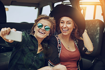 Buy stock photo Cropped shot of two young friends taking a selfie while on a roadtrip together