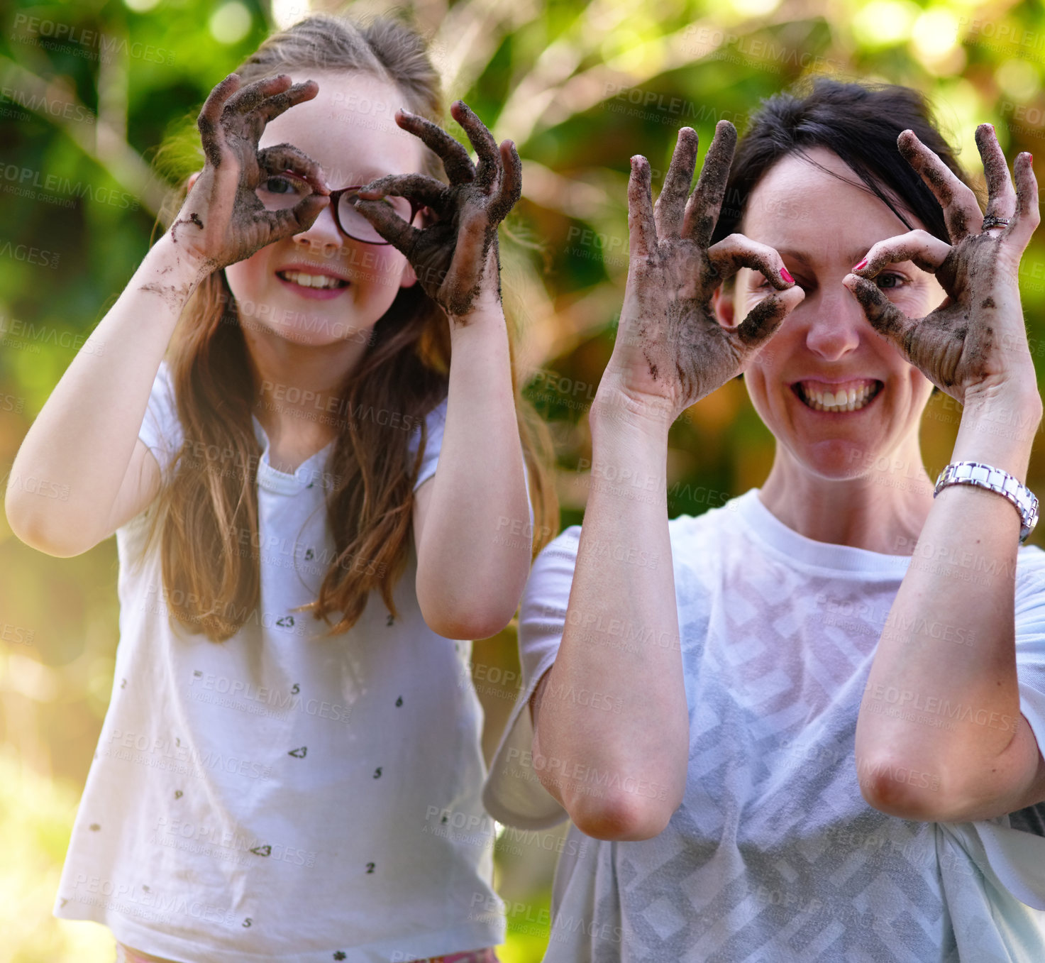 Buy stock photo Portrait of a mother and her little daughter covering their eyes with their muddy hands outside