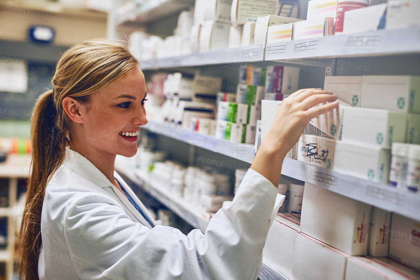 Buy stock photo Shot of a pharmacist looking at medication on a shelf
