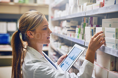 Buy stock photo Shot of a pharmacist using her digital tablet while working in a isle