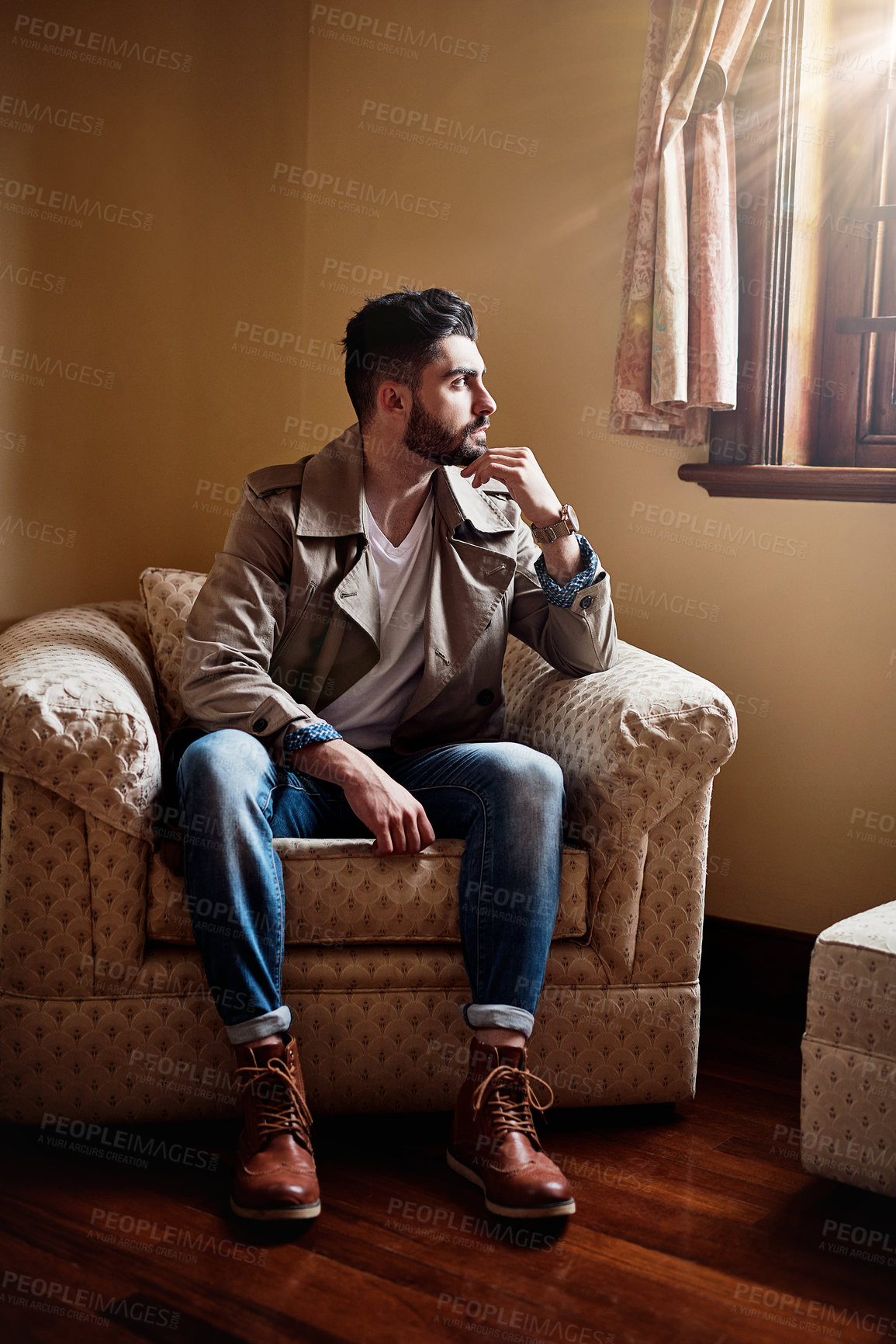 Buy stock photo Shot of a handsome young man deep in thought while sitting on a chair at home