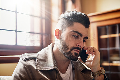 Buy stock photo Shot of a handsome young man talking on a cellphone at home
