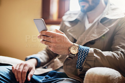 Buy stock photo Cropped closeup shot of an unrecognizable young man sitting in a chair using a cellphone