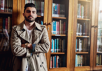 Buy stock photo Portrait of a handsome and stylish young man leaning against a bookcase at home