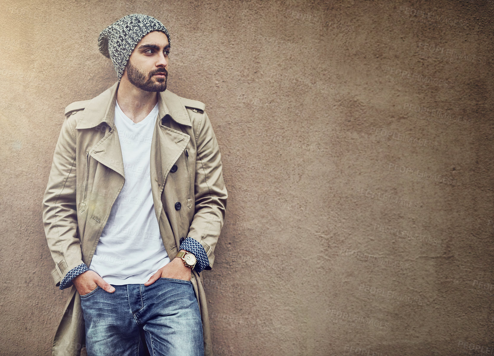 Buy stock photo Shot of a fashionable young man wearing urban wear and posing against a brown wall