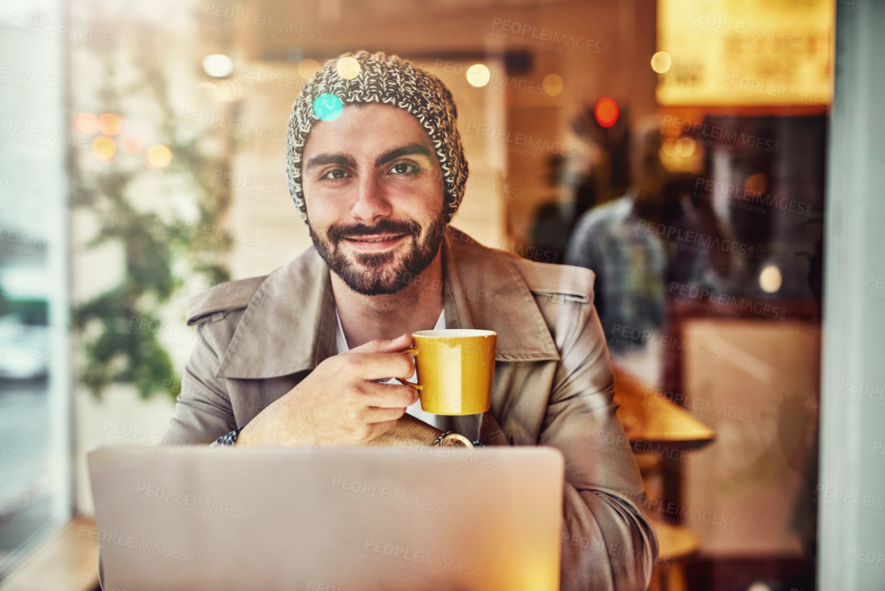 Buy stock photo Portrait of a stylish young man smiling while drinking a coffee and using a laptop in a cafe