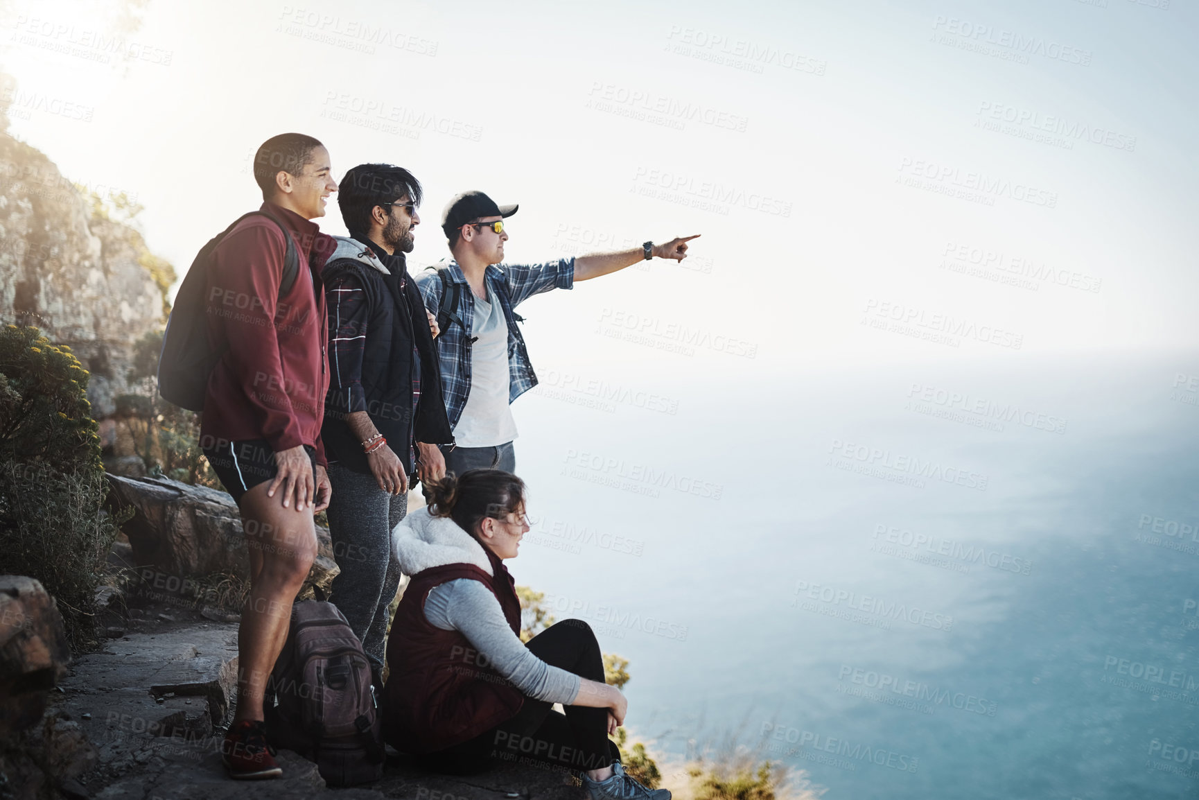 Buy stock photo Shot of a young man pointing something out to his friends while on a mountain hike