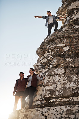 Buy stock photo Shot of a young man pointing something out to his friends while on a mountain hike