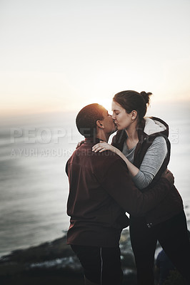 Buy stock photo Cropped shot of an affectionate young couple kissing after scaling a mountain