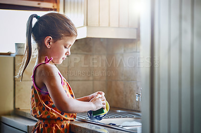 Buy stock photo Cropped shot of a little girl washing dishes at home