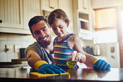 Buy stock photo Cropped shot of a father and his little daughter cleaning a kitchen surface together at home