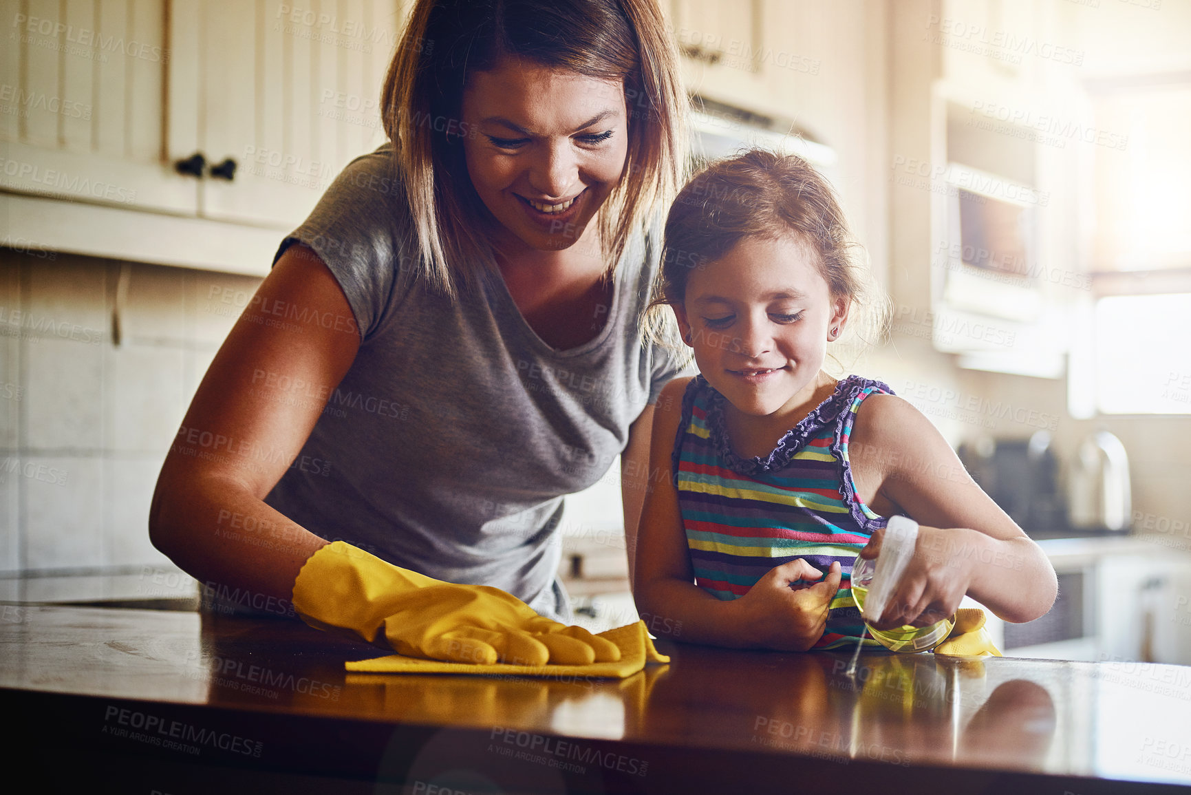 Buy stock photo Cropped shot of a mother and her little daughter cleaning a kitchen surface together at home