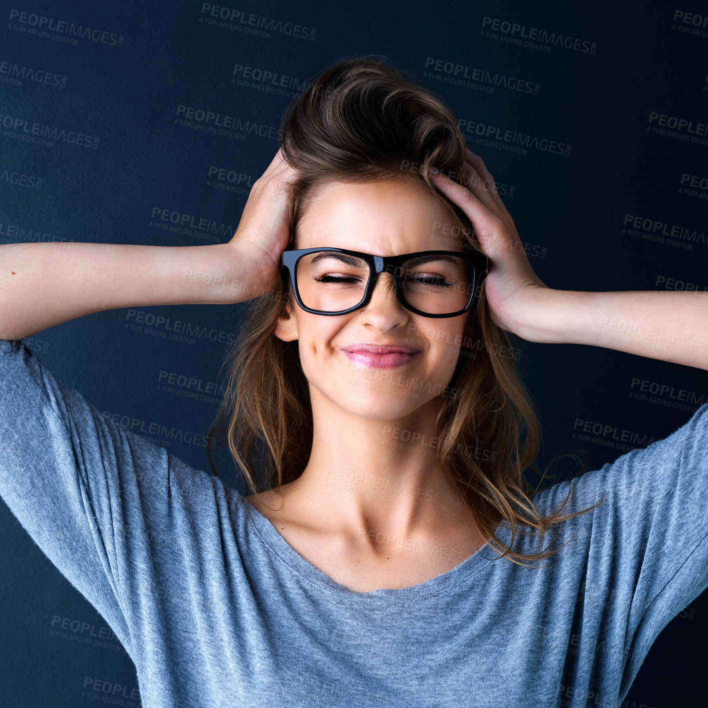 Buy stock photo Studio shot of a cute teenage girl in glasses with her hands in her hair posing against a dark background