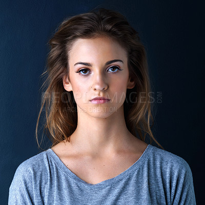 Buy stock photo Studio shot of an expressionless teenage girl posing against a dark background