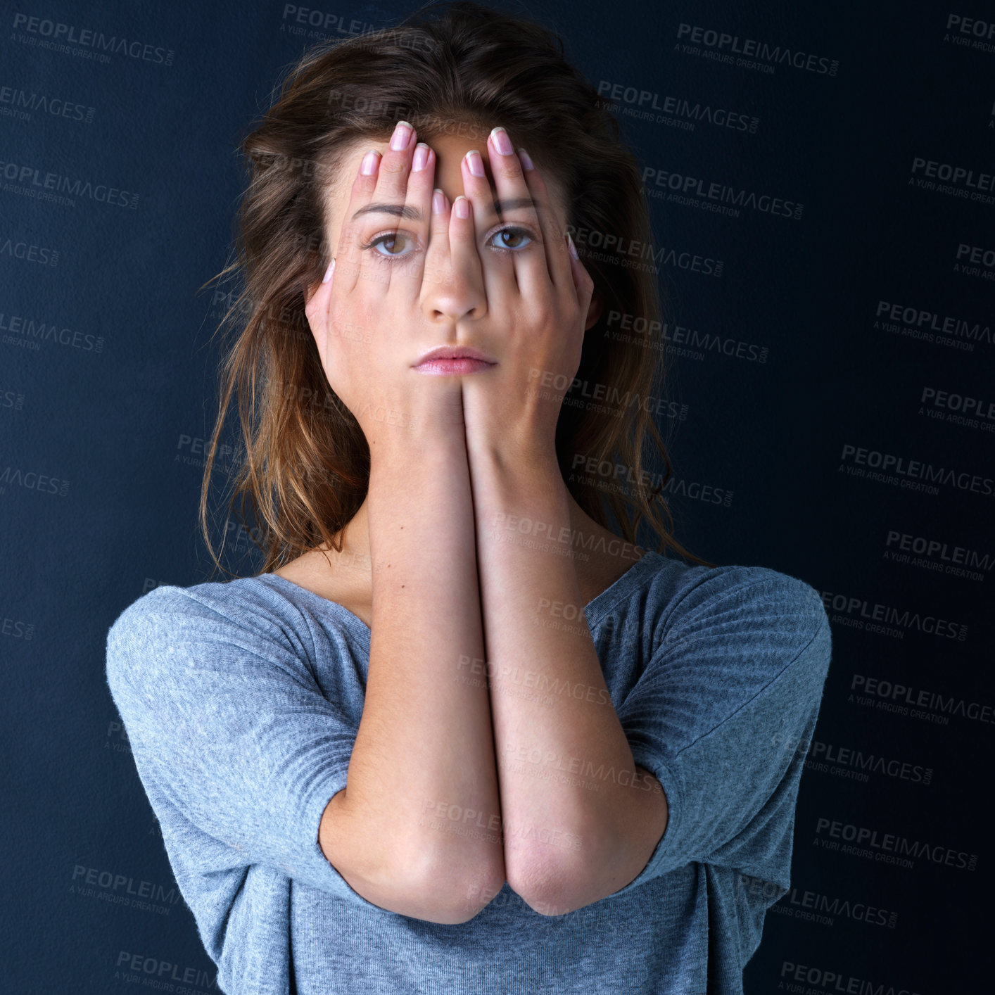 Buy stock photo Studio shot of a teenage girl with her face superimposed on hands covering her eyes against a dark background