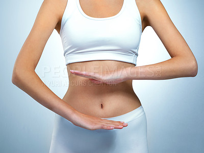 Buy stock photo Shot of an unidentifiable young woman posing with her hands over her stomach in the studio