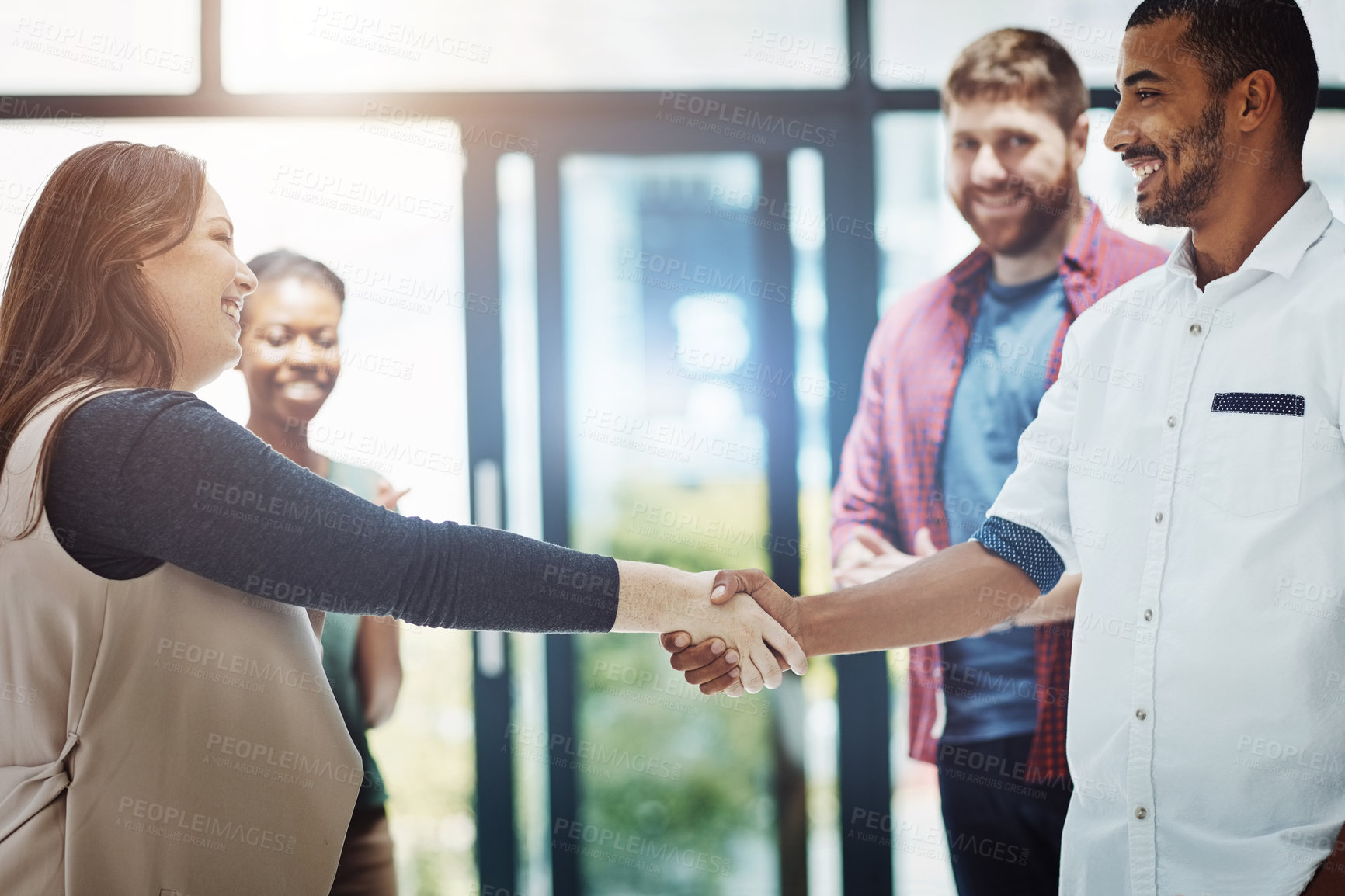 Buy stock photo Business people giving handshake, welcoming new employee and standing united while colleagues clap in meeting at work. Coworkers shaking hands, celebrating success or congratulating on a promotion