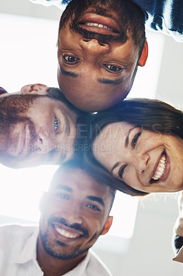 Buy stock photo Portrait of a diverse group of happy office workers from below joining together in a huddle for support and unity with lights in the background. Cheerful motivated colleagues ready for business
