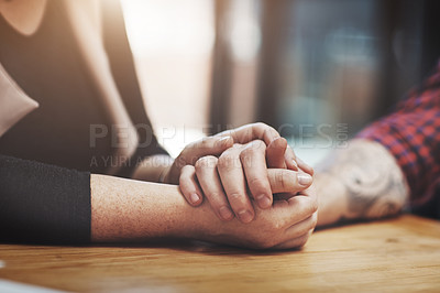 Buy stock photo Support, compassion and trust while holding hands and sitting together at a table. Closeup of a loving, caring and affectionate couple comforting and helping each other through a difficult time