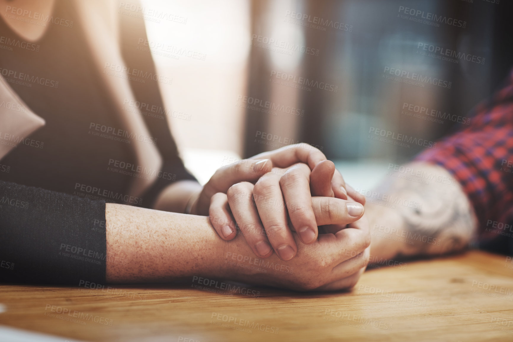 Buy stock photo Support, compassion and trust while holding hands and sitting together at a table. Closeup of a loving, caring and affectionate couple comforting and helping each other through a difficult time
