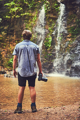 Buy stock photo Rearview shot of a young photographer admiring a waterfall in the jungle