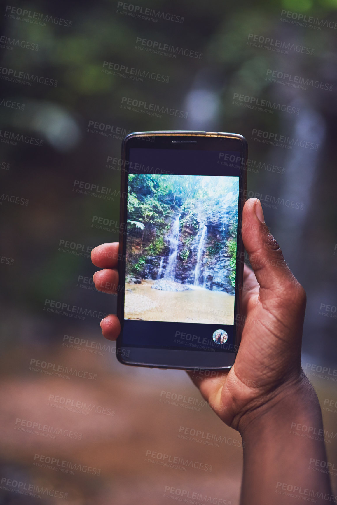 Buy stock photo Shot of an unidentifiable young tourist taking a picture of a waterfall with his smartphone