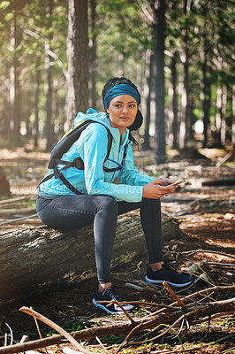 Buy stock photo Full length shot of an athletic young woman sending a text while jogging in the woods