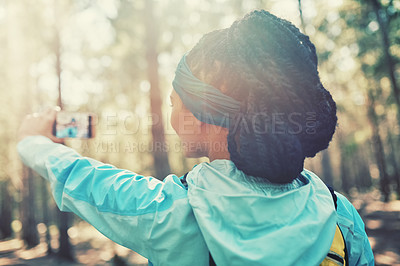 Buy stock photo Cropped shot of an athletic young woman taking selfies while jogging in the woods