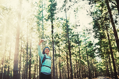Buy stock photo Cropped shot of an athletic young woman taking selfies while jogging in the woods