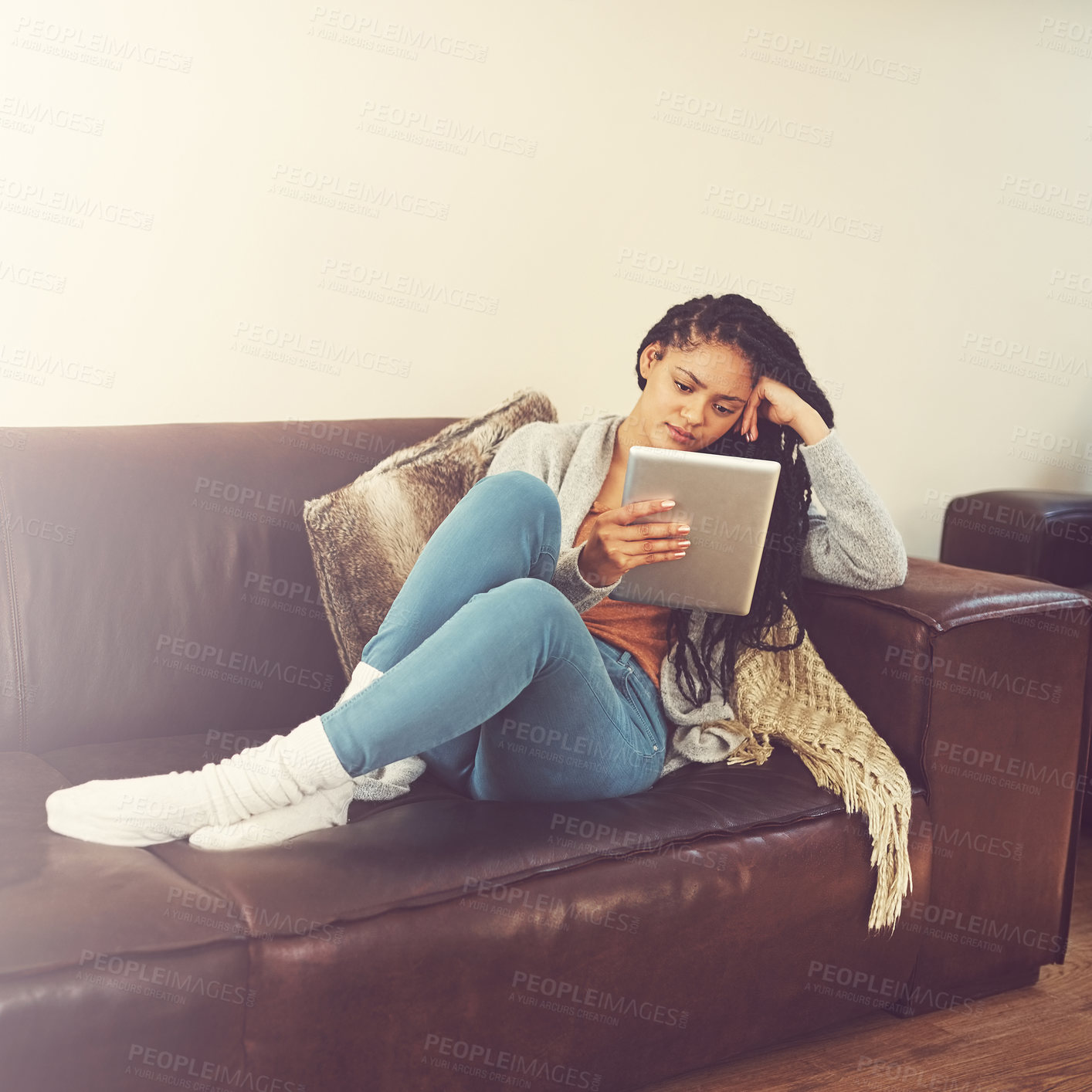 Buy stock photo Shot of a young woman using her tablet while relaxing at home