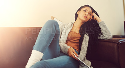 Buy stock photo Shot of a young woman contemplating while relaxing at home with her tablet