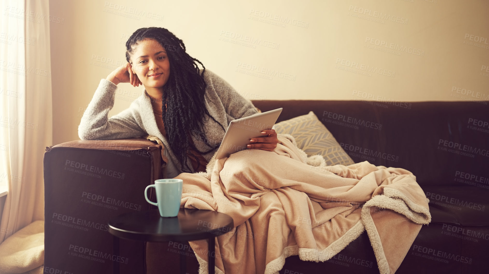 Buy stock photo Shot of a young woman using her tablet while relaxing at home