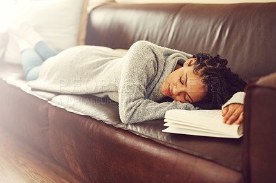 Buy stock photo Shot of a young woman asleep on her couch with a book in front of her