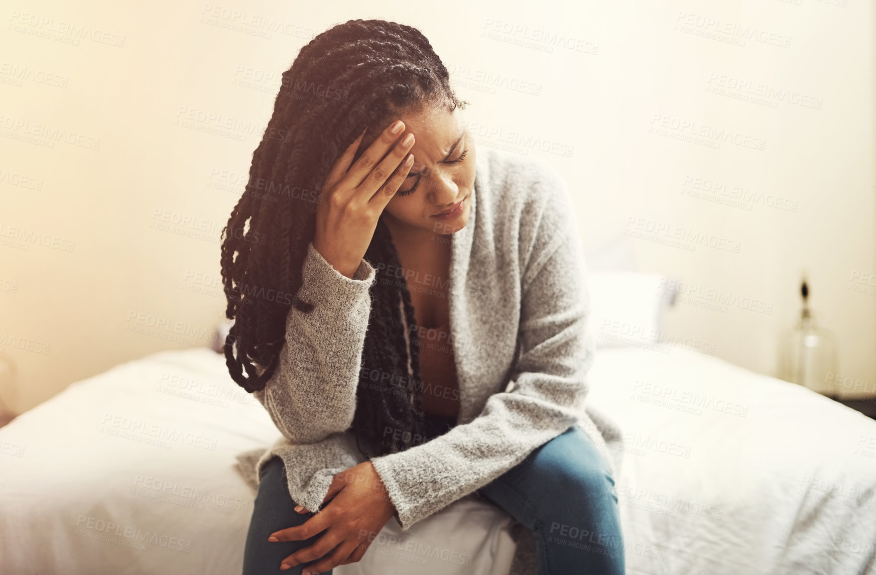 Buy stock photo Shot of a young woman looking depressed while sitting on her bed