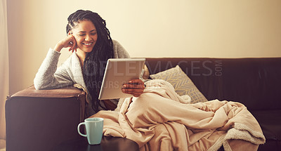 Buy stock photo Shot of a young woman using her tablet while relaxing at home
